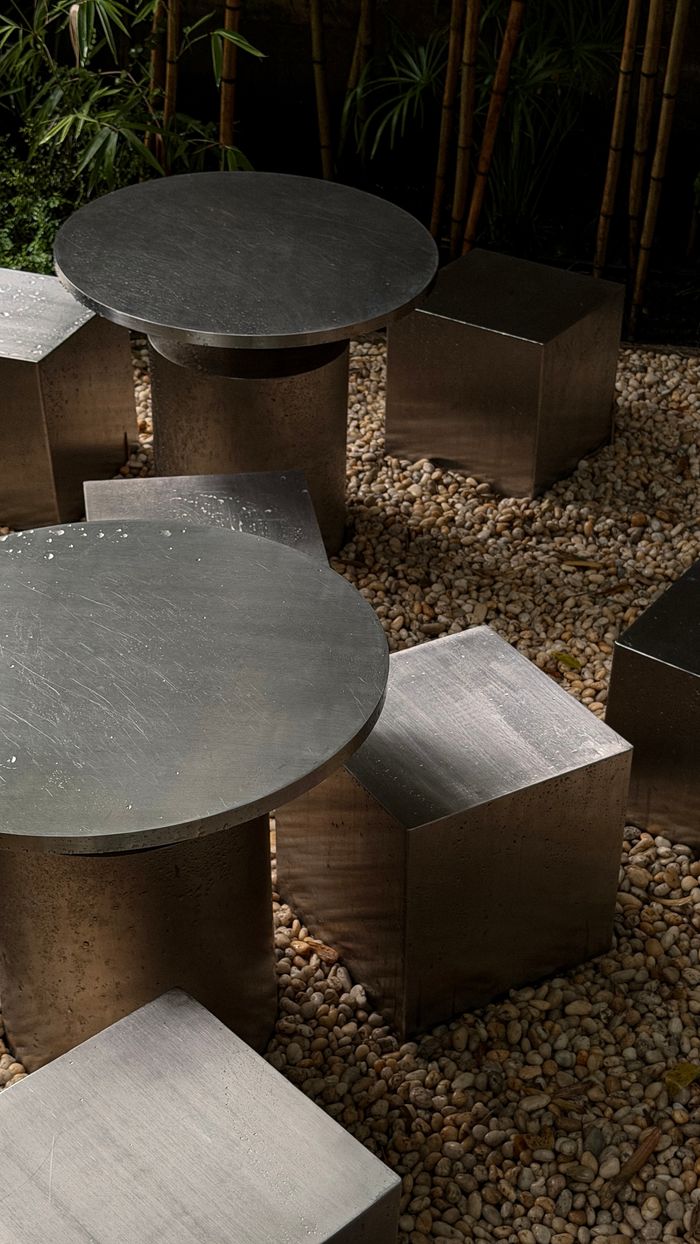 Contemporary metal seating on a pebble patio, surrounded by bamboo in Ho Chi Minh City.